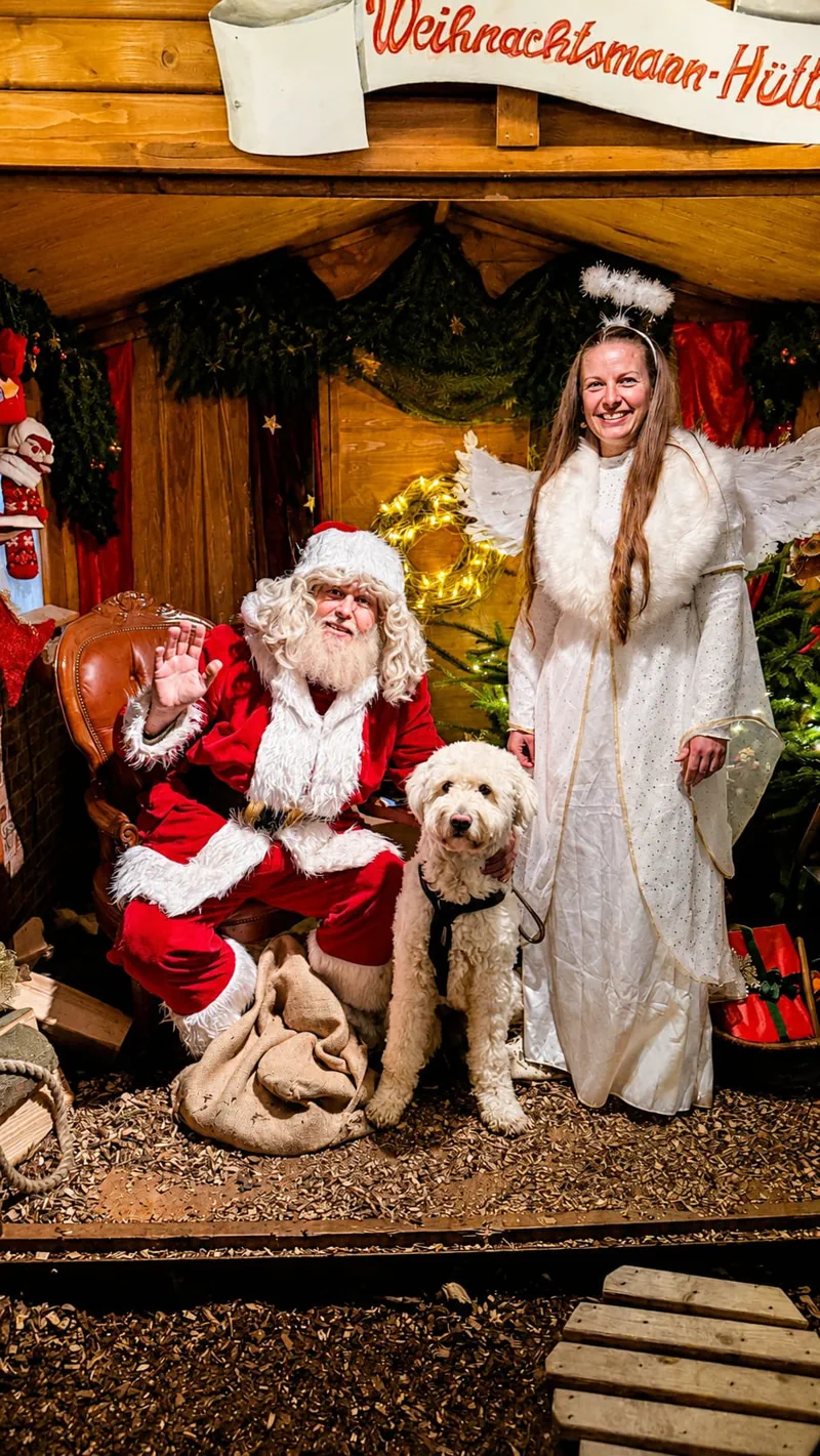 Weihnachtsmann und Engel in der Weihnachtsmann-Hütte mit Hund